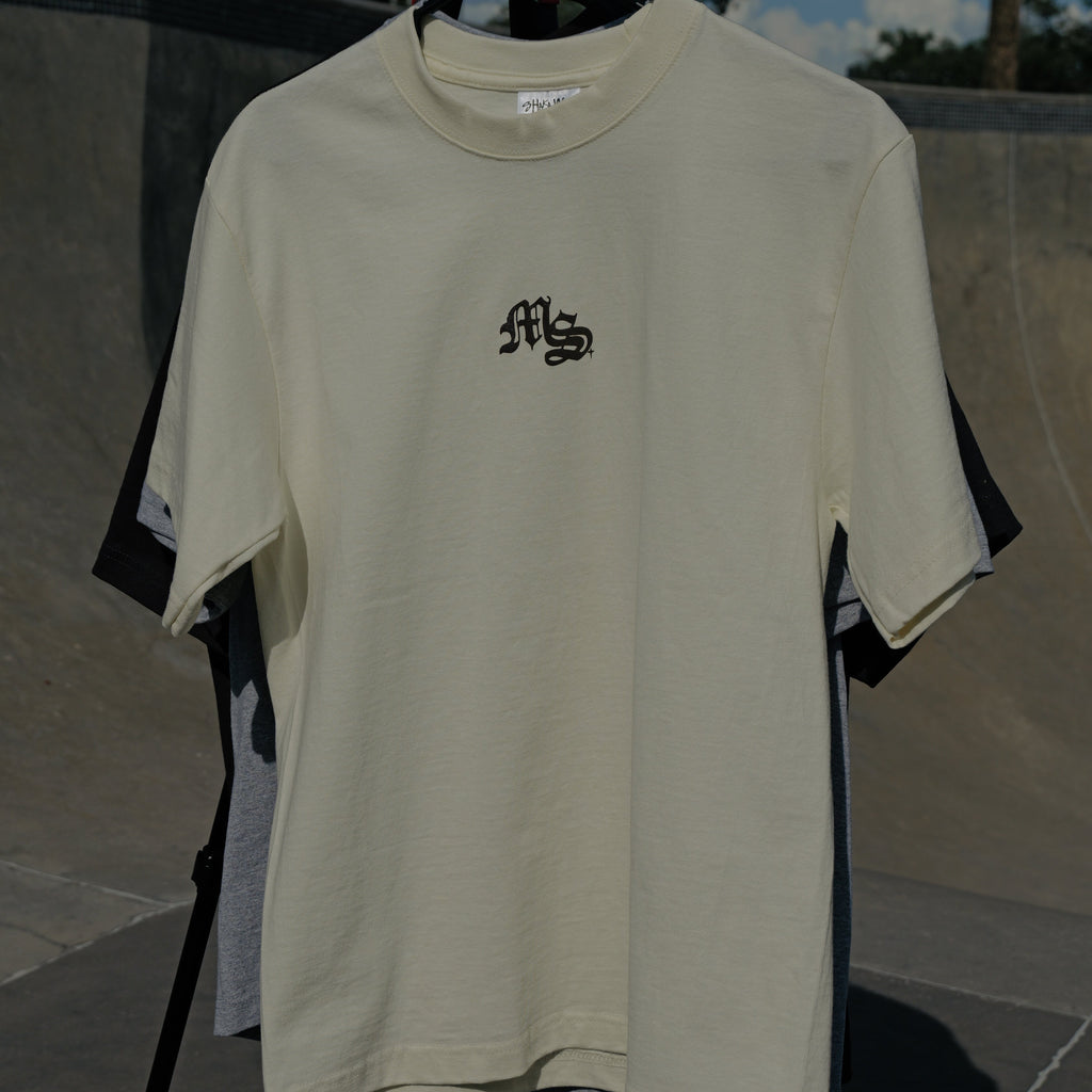 Beige t-shirt with a logo on a hanger against a skate park background
